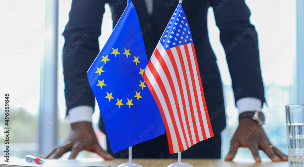 American flag and flag of European Union with businessman near by.