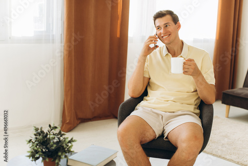 A handsome guy in yellow casual clothes is sitting at home and talking on the phone Free Download A handsome guy in yellow casual clothes is sitting at home and talking on the phone - GFXLoad