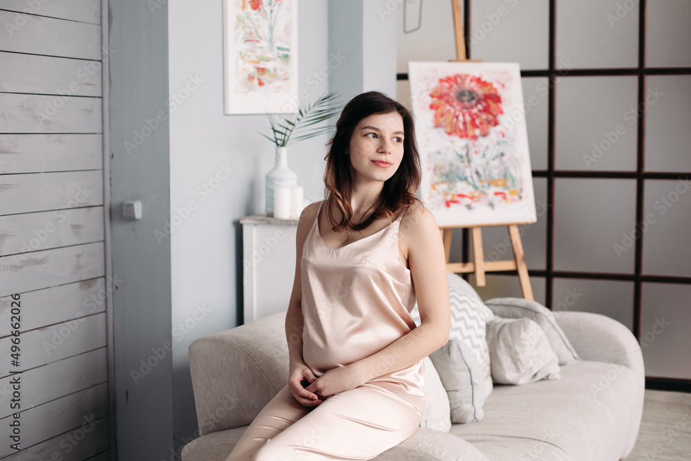 A pregnant woman is sitting on the couch in her pajamas at home A pregnant woman is sitting on the couch in her pajamas at home