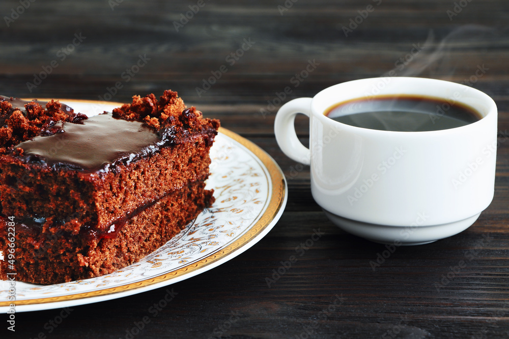 A piece of Chocolate cake on a plate and cup of black coffee on a wooden background.Slice of Homemade brownie cake.Copy space A piece of Chocolate cake on a plate and cup of black coffee on a wooden background.Slice of Homemade brownie cake.Copy space