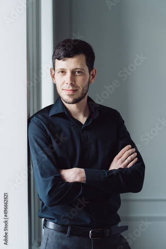 Caucasian young man portrait holding arms crossed, wearing black shirt on light background © arthurhidden