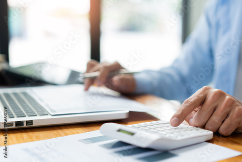 Business analyst concept the male accountant concentrating on sale detail while pressing his calculator