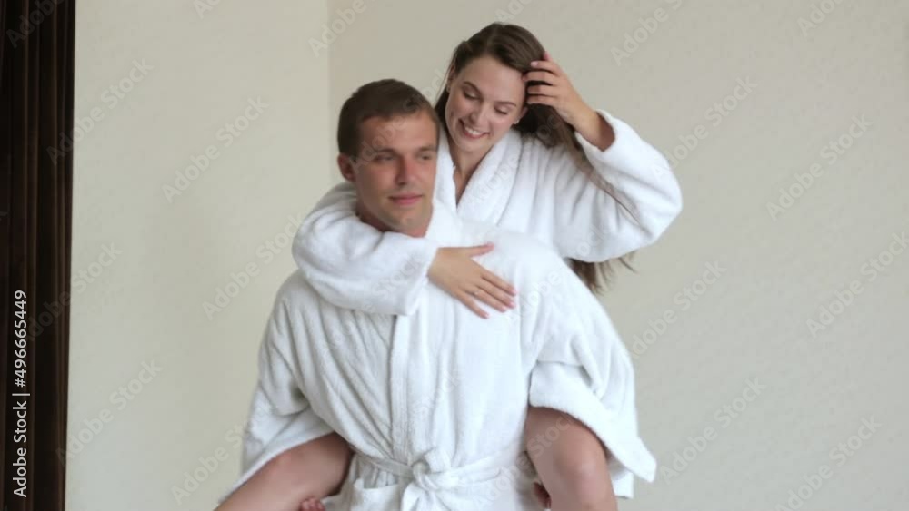 Ukrainian newlyweds sit on the bed and look at each other with love. Attractive handsome young man and woman wearing bathrobes are enjoying the morning in the bedroom at home. The concept of family Ukrainian newlyweds sit on the bed and look at each other with love. Attractive handsome young man and woman wearing bathrobes are enjoying the morning in the bedroom at home. The concept of family