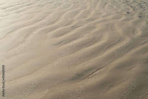 Sand texture waves close up. Abstract background pattern of wet sand beach.