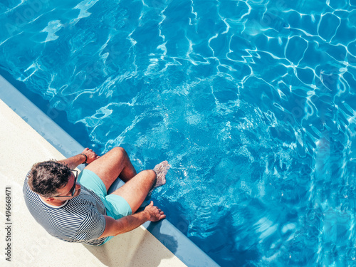 Photography Fashionable man sitting by the pool  on the empty deck of a cruise liner