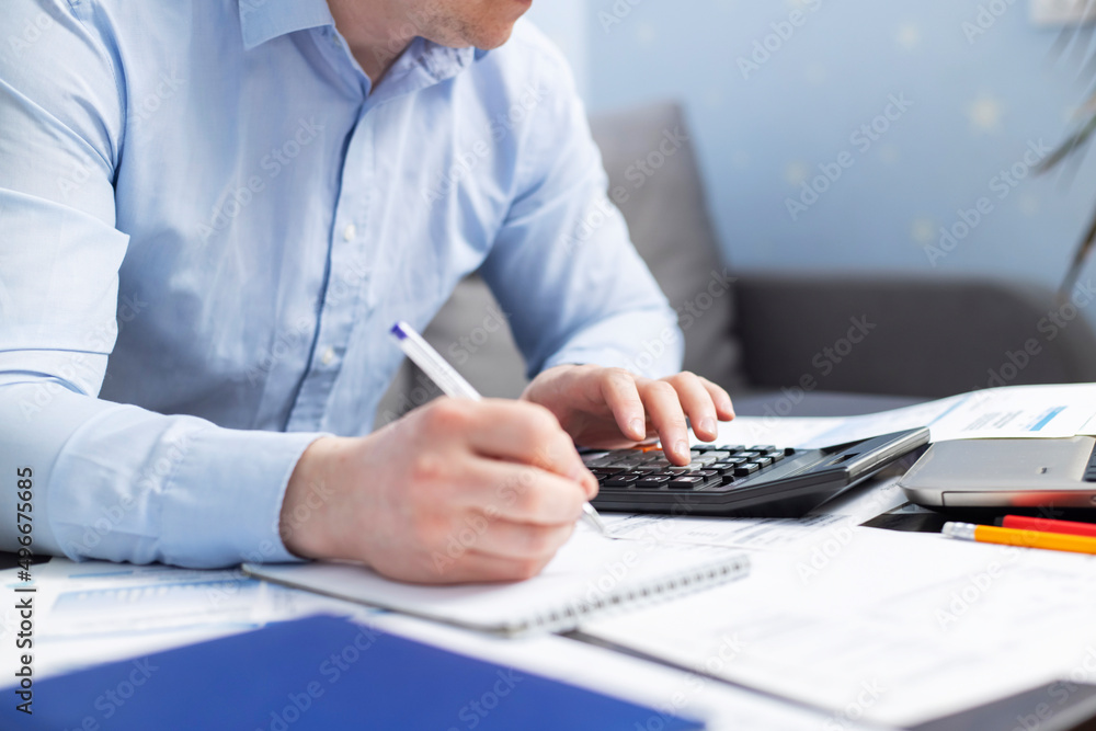 Man with bills and calculator. Businessman using calculator to calculate bills at the table in office. Financial accounting concept Man with bills and calculator. Businessman using calculator to calculate bills at the table in office. Financial accounting concept