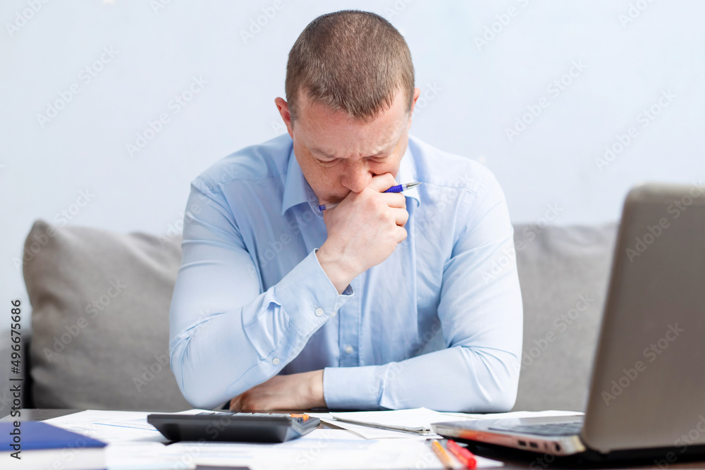 Distressed young man sit at desk paying bills feel stressed having financial problems. Unhappy upset male frustrated by debt or bankruptcy managing household budget or expenses Distressed young man sit at desk paying bills feel stressed having financial problems. Unhappy upset male frustrated by debt or bankruptcy managing household budget or expenses