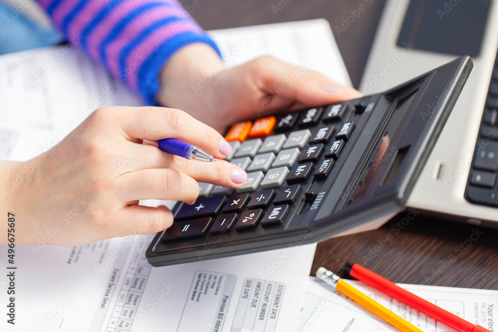 Woman using calculator for calculate domestic bills at home, doing paperwork for paying taxes Woman using calculator for calculate domestic bills at home, doing paperwork for paying taxes