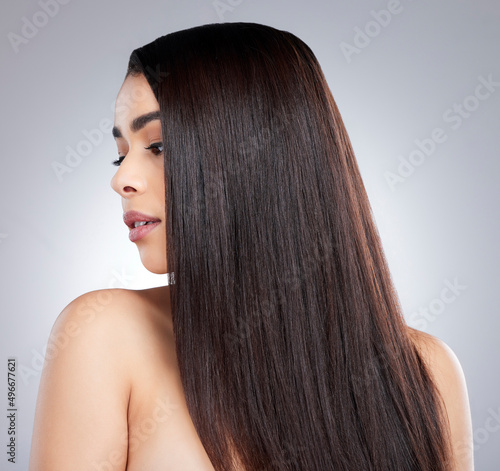Every strand perfectly on point. Studio shot of an attractive young woman posing against a grey background.
