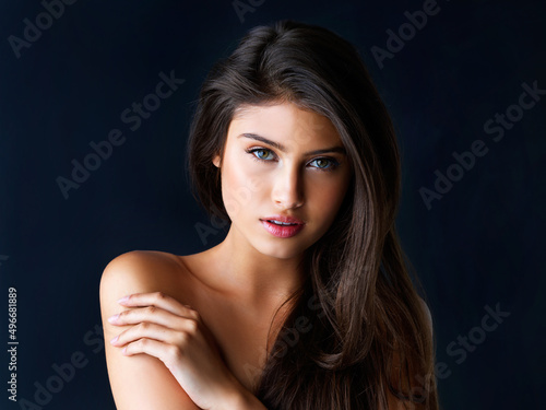 Just one look and youre hooked. Cropped portrait of a gorgeous young woman posing against a dark background. photo