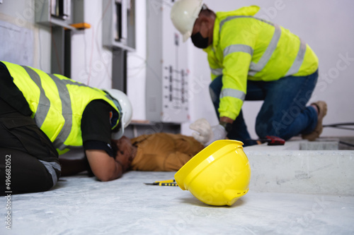 Safety helmet yellow of maintenance worker lying unconscious on floor in the factory control room in background.