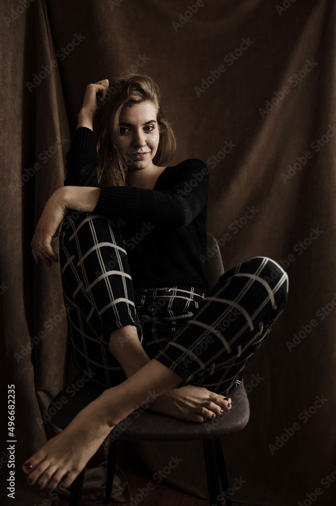 beautiful girl in a good mood laughs while sitting on a chair. a girl in pajamas sits on a chair at home. portrait of a beautiful woman beautiful girl in a good mood laughs while sitting on a chair. a girl in pajamas sits on a chair at home. portrait of a beautiful woman