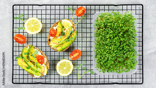 Growing microgreens at home. Recipes for sandwiches and snacks with microgreens of peas, arugula, broccoli. Quick meal variants with microgreens and avocados for breakfast served on baking rack.
