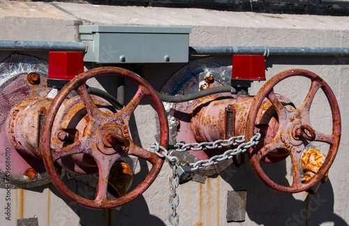 The photo shows two rusted shut-off valves in the sun secured by a lock