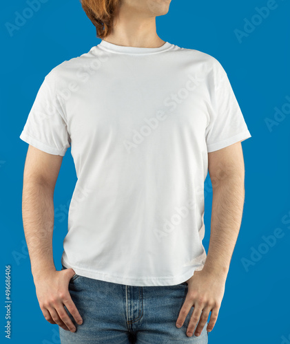 White t-shirt for mock-up print design. A young man wears a short-sleeved t-shirt, jeans, studio shot on a red background. Guy in white clothes for advertising