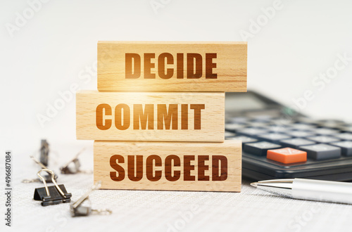 On the reports is a pen, calculator, clips and wooden boards with the inscription - DECIDE COMMIT SUCCEED