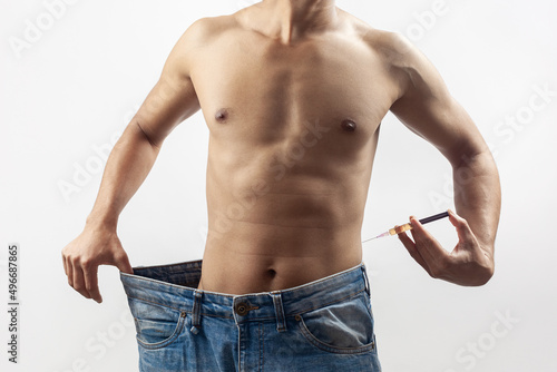One Caucasian male with oversize blue colour jeans using lipotropic injection for get rid of extra body fat isolated in white background.