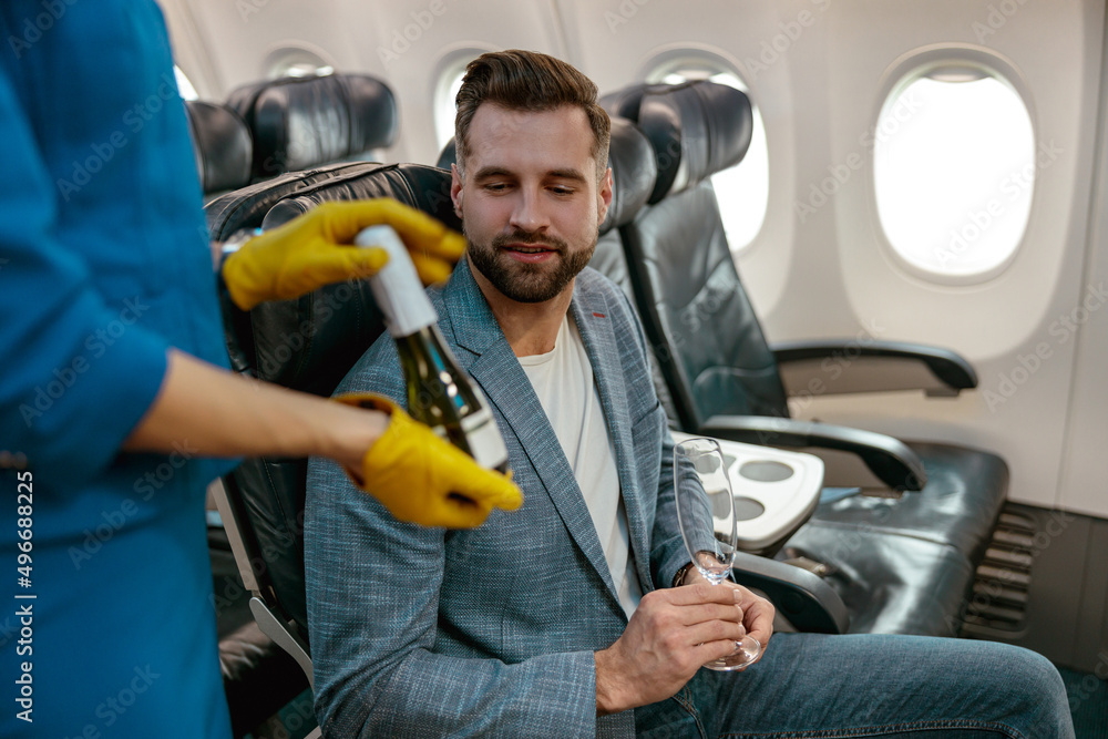 Flight attendant offering champagne to man in airplane Flight attendant offering champagne to man in airplane