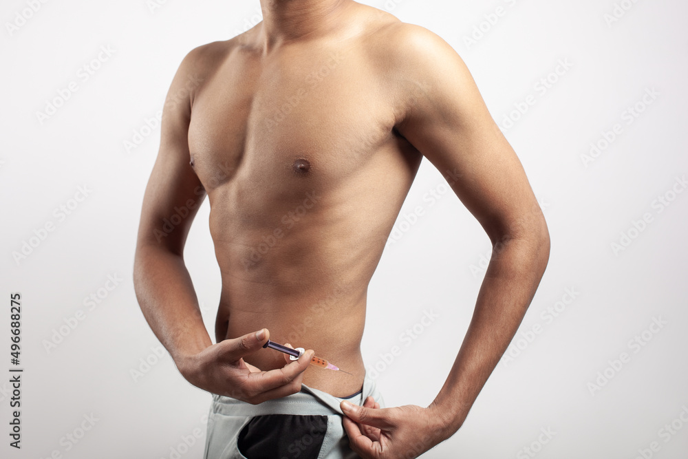 Naklejka premium shirtless young asian muscular guy injecting insulin on his waist.