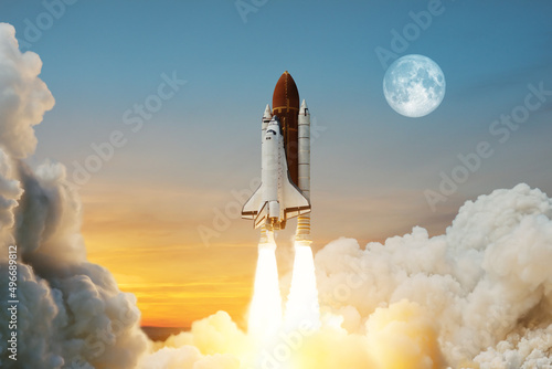 Spaceship lift off. Space shuttle with smoke and blast takes off into space on a background of a sunset with a full moon in the sky. Elements of this image furnished by NASA.