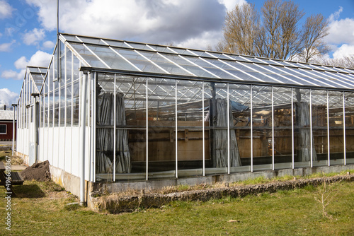 Glass greenhouse in early spring against a cloudy sky. High quality photo