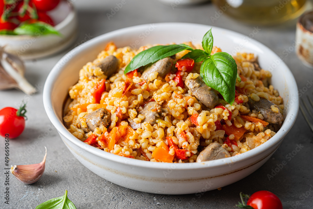 bulgur with chicken hearts and vegetables. Delicious healthy dish on a gray background. Bulgur pilaf