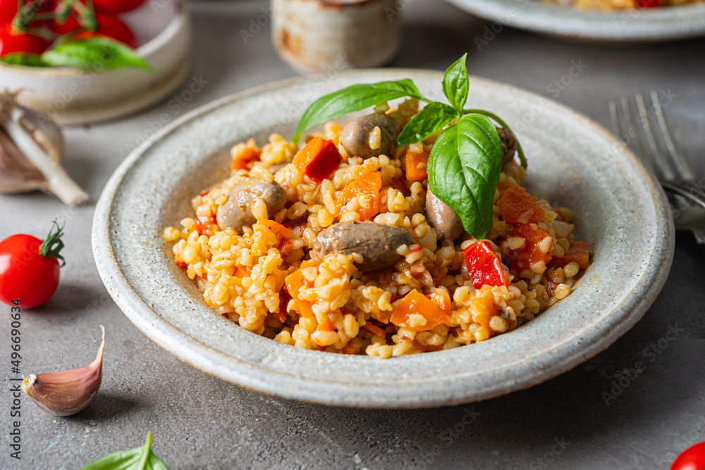 bulgur with chicken hearts and vegetables. Delicious healthy dish on a gray background. Bulgur pilaf