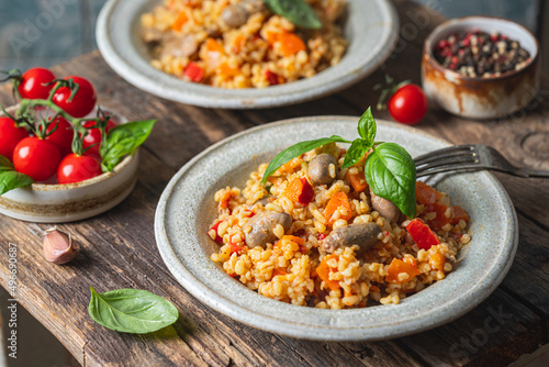 bulgur with chicken hearts and vegetables. Delicious healthy dish on dark background. Bulgur pilaf