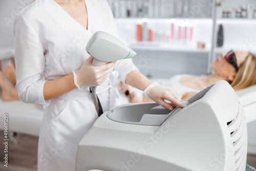 Woman beautician using laser epilation machine in beauty salon photo