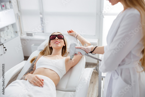 Smiling woman receiving laser epilation treatment in beauty salon photo