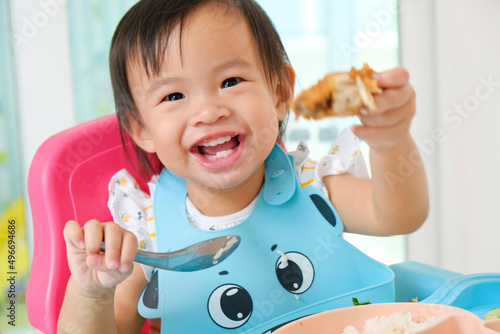 Happy eating Asian girl 1 year old by herself with Baby Led Weaning (BLW) method, Self-Feeding photo