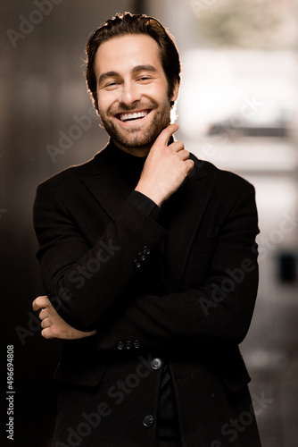 Portrait of overjoyed male in stylish suit, smiling with his eyes closed, posing at the photoshoot. Handsome businessman in fashion cloth happy about well done work of his project, success concept