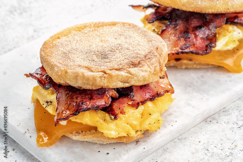 Canvastavla English muffin, scrumbled egg, ham, and cheese breakfast sandwich on a cutting b