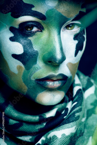Fototapeta Naklejka Na Ścianę i Meble -  Beautiful young fashion woman with military style clothing and face paint make-up, khaki colors, halloween celebration close up, green pattern