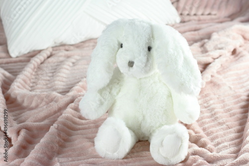 White fluffy bunny toy on pink blanket, rabbit sitting on bed