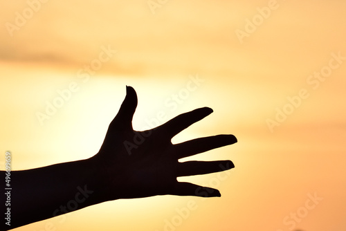 Silhouette of a hand over the sky at sunset
