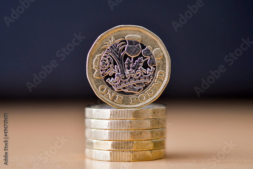 British one pound coin standing on its edge on top of a column of coins. No people. photo