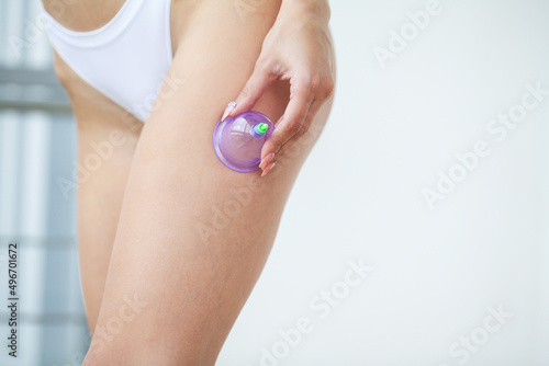 Anti-cellulite massage of the hips with the use of vacuum cans.