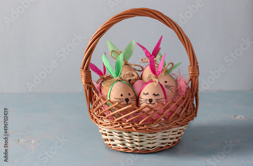 Easter bunnies made of eggs with multi-colored ears made of colored paper lokated in basket on blue background photo