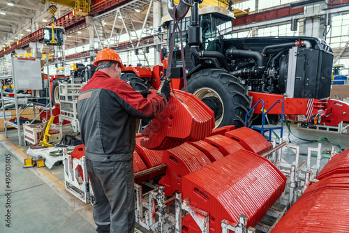 Canvas-taulu Industrial worker assembles agricultural equipment in tractor or combine harvester production line in factory
