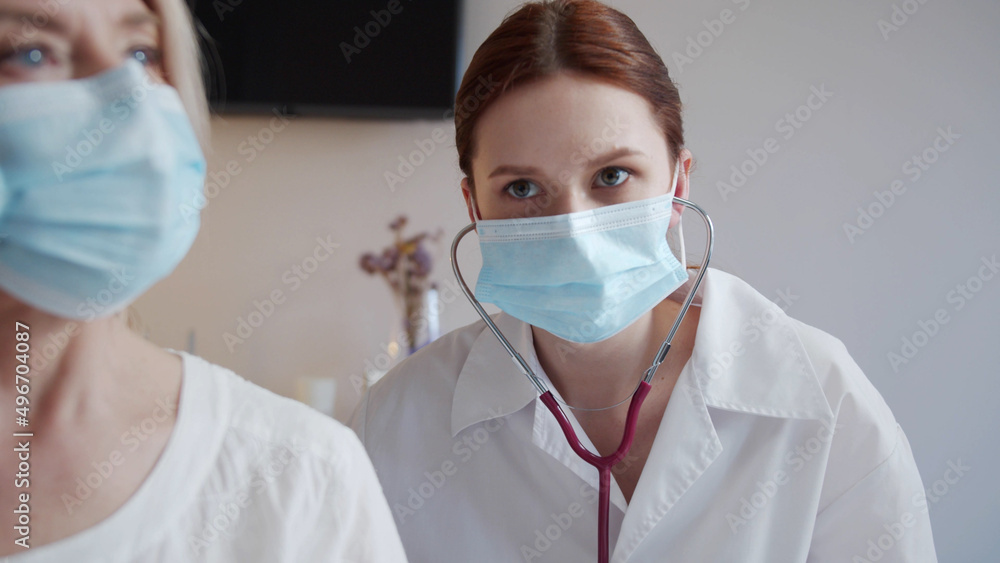 An elderly patient removes her jacket so that the doctor can listen to her lungs with a stethoscope An elderly patient removes her jacket so that the doctor can listen to her lungs with a stethoscope