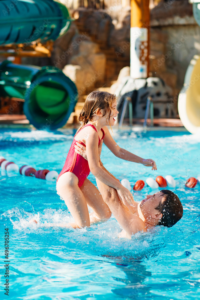 dad throws up his daughter, they have fun and play together in the pool. 