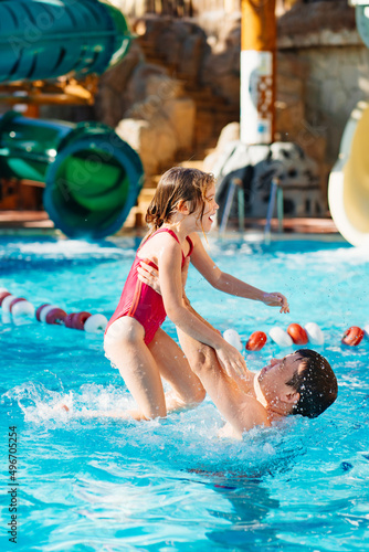 dad throws up his daughter, they have fun and play together in the pool.  © andrey