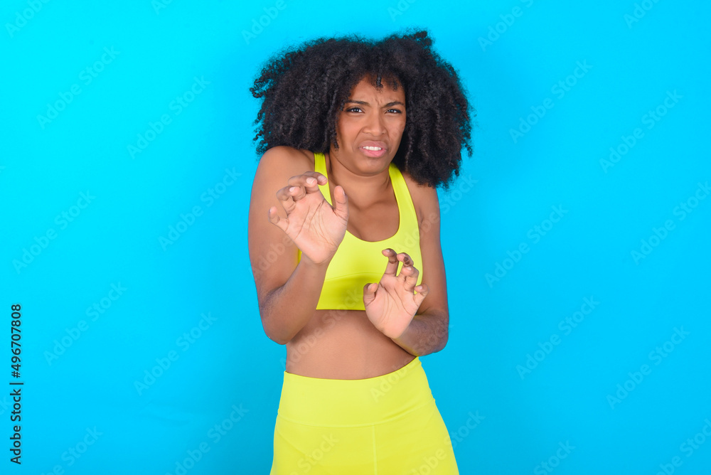 Ugh how disgusting! Displeased young woman with afro hairstyle in sportswear against blue background, has dissatisfied facial expression as sees something abominable. Ugh how disgusting! Displeased young woman with afro hairstyle in sportswear against blue background, has dissatisfied facial expression as sees something abominable.