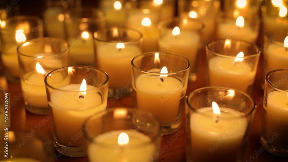 Camera moves past rows of glowing candles in a church or temple. Camera moves past rows of glowing candles in a church or temple.