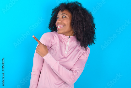 Canvas Print young woman with afro hairstyle in technical sports shirt against blue backgroun