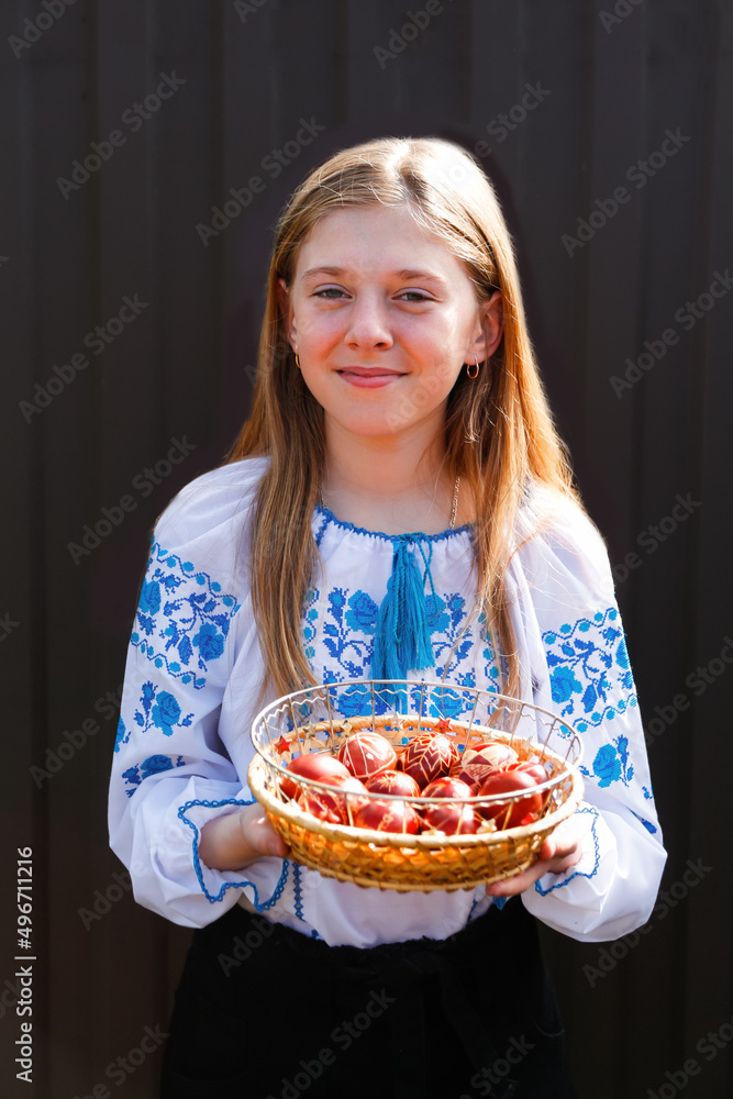 Defocus ukrainian smiling girl in vyshyvanka holding basket of colored red eggs on black background. Easter, Ukraine. Craft eggs. Collection of pysanka or krashanka. Closeup. Out of focus