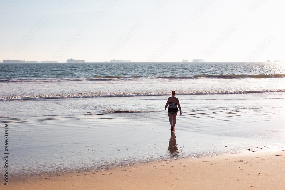silhouette of woman walking into the sea