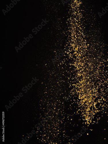 Golden stream of spices in frozen flight on a black background. Aromatic additives, seasonings, spices. Cooking, oriental cuisine, ingredients, flavorings for various dishes. Restaurant, hotel.