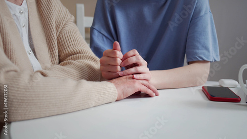 Daughter visiting elderly mother. They sit at the table and talk about serious things